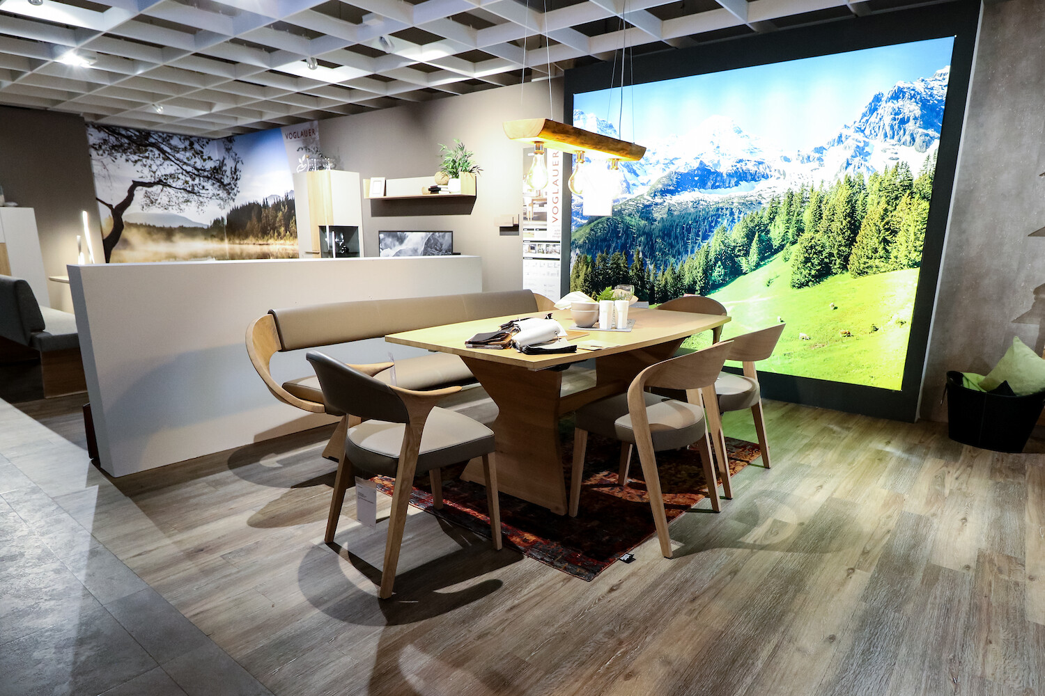 Blick in Ausstellungsraum zeigt Tisch mit Stühlen und einer Bank.