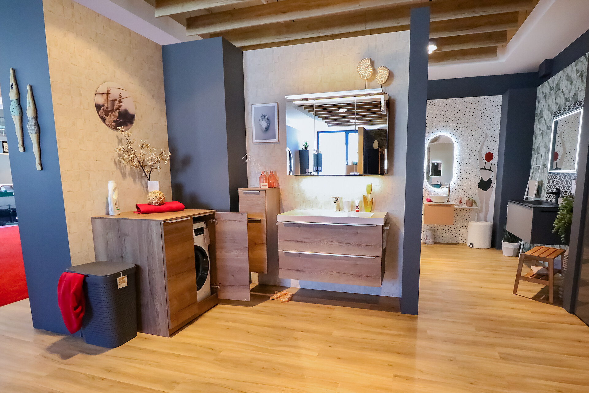 Ausstellungsraum zeigt Badezimmer mit Spiegel, Waschbecken und Waschmaschinenschrank.