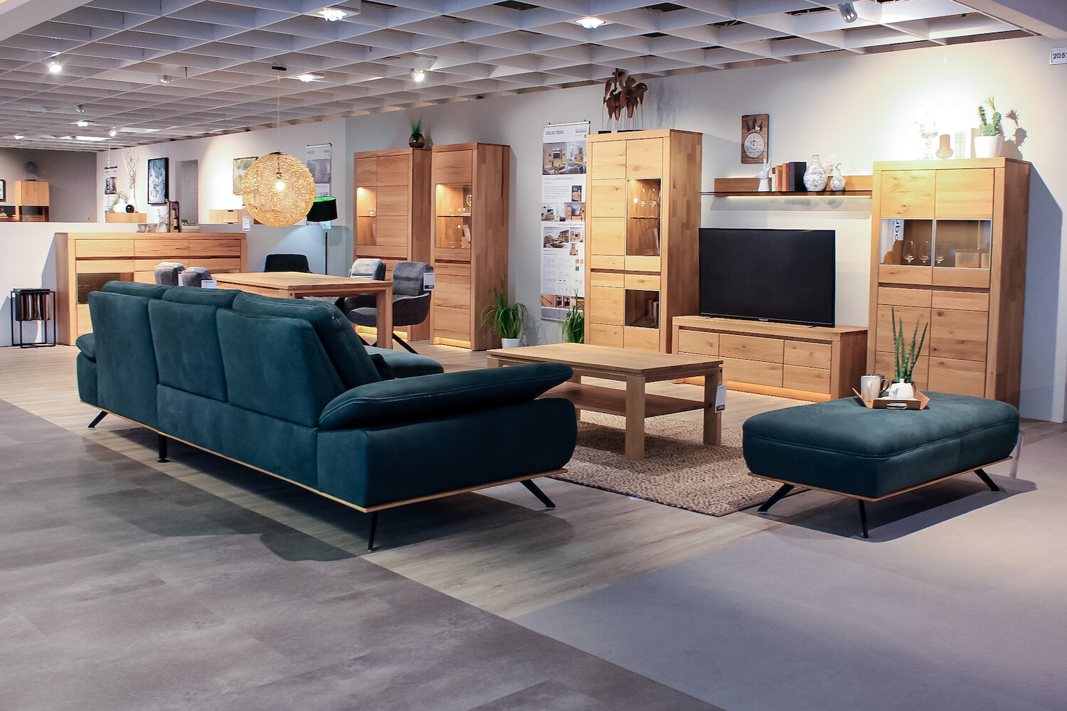 Blick in Ausstellungsraum zeigt eine Couch von hinten, einen Couchtisch, einen Hocker, eine TV-Bank und Schränke.