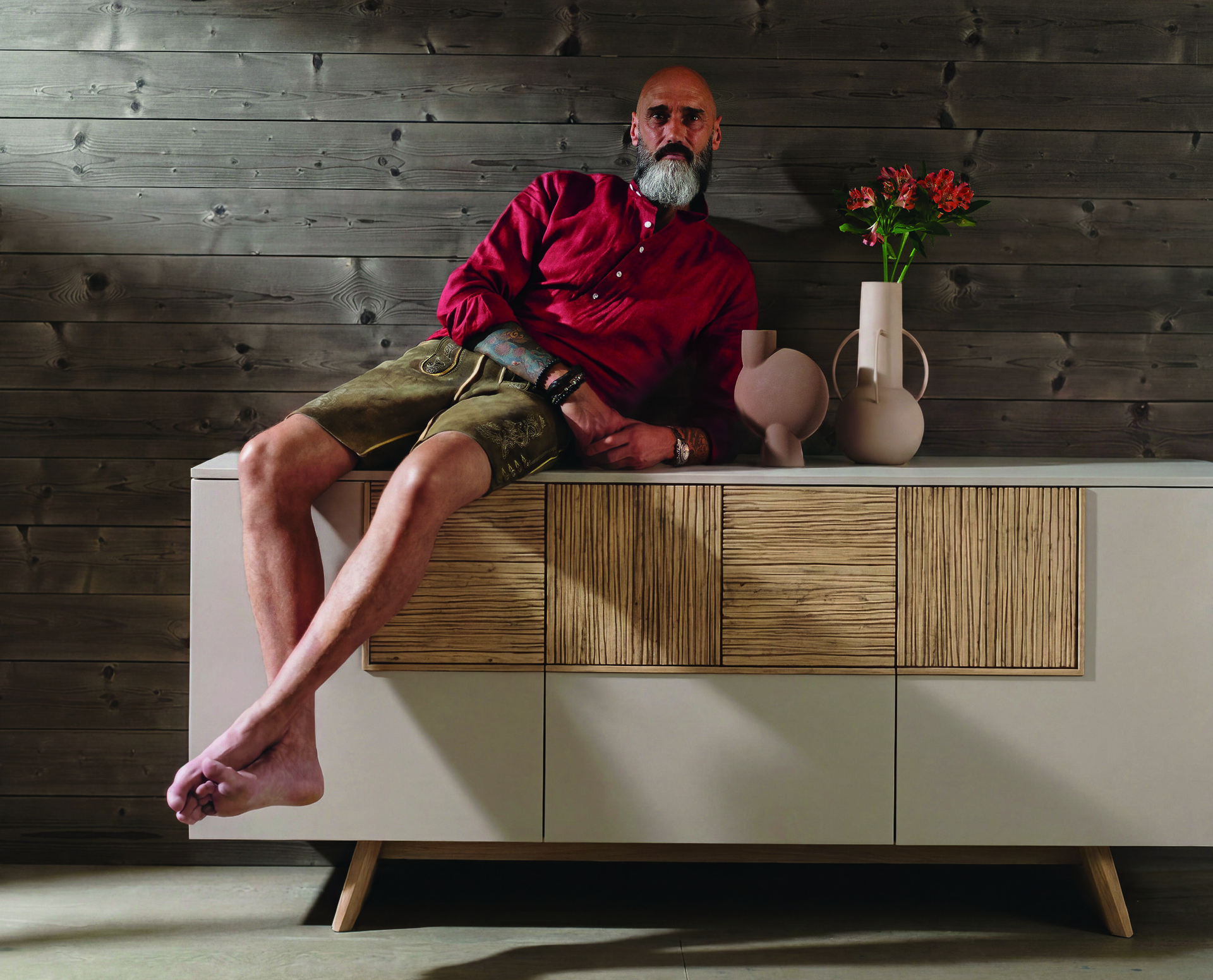 Ein Mann sitzt lässig auf einem Sideboard.